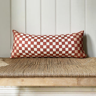 Checkered pillow on a wooden bench against a paneled wall