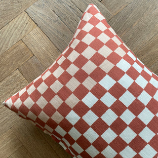 Checkered pillow with red and white pattern on a wooden floor
