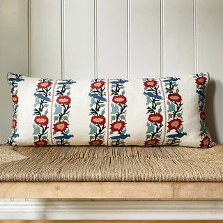 Decorative pillow with floral pattern on a wooden bench against a paneled wall.