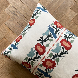 Decorative pillow with floral and bird pattern on a wooden floor