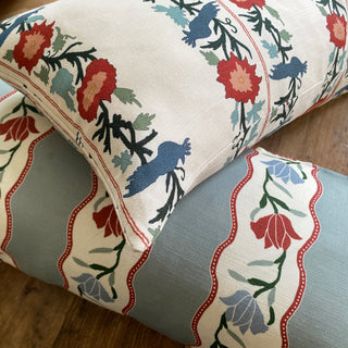 Decorative pillows with floral and bird pattern on a wooden floor