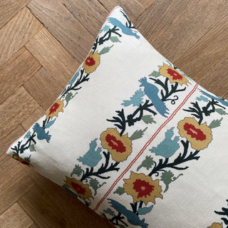 Decorative pillow with floral and bird pattern on a wooden floor
