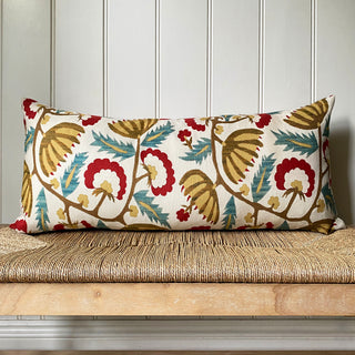 Decorative pillow with floral pattern on a wooden bench against a paneled wall.