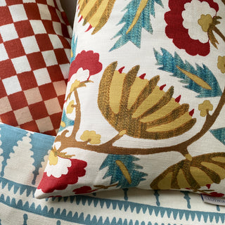 Decorative pillow with floral and bird pattern on a checkered fabric background