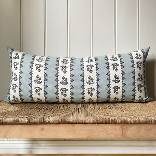 Decorative pillow with a geometric pattern on a wooden bench against a paneled wall.