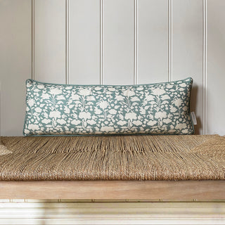 Floral patterned pillow on a woven bench against a paneled wall.