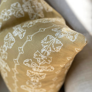 A close up of a square cushion with a floral stripe in hay yellow.