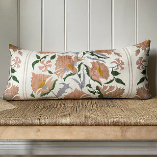 Floral patterned pillow on a wooden bench against a paneled wall.