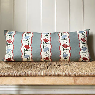 Decorative pillow with floral pattern on a wooden bench against a paneled wall.