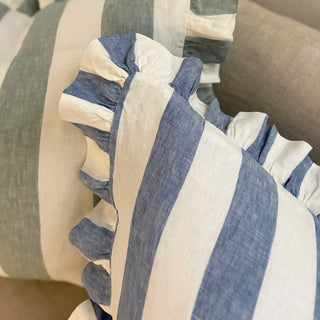 A close up of a blue and white striped cushion with frill leaning against and green and white striped cushion.