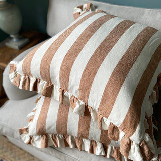 Striped terracotta cushion pillow with frills on a sofa