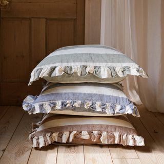 Stack of three decorative cushion pillows with frilled edges on a wooden floor.